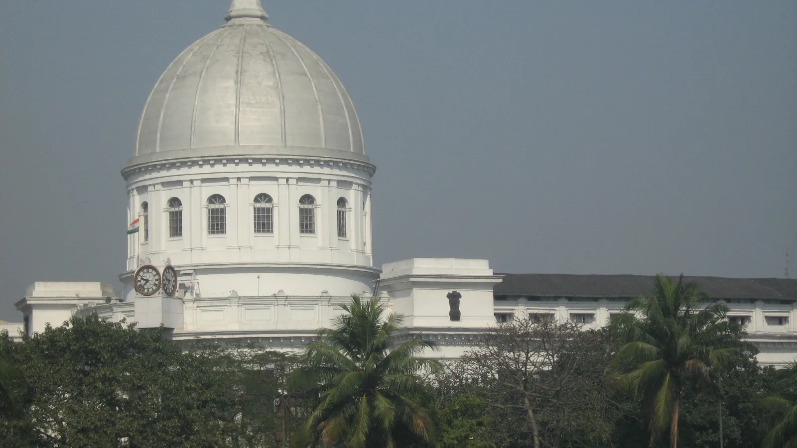 The domed General Post Office building in Kolkata seen above a line of palm trees