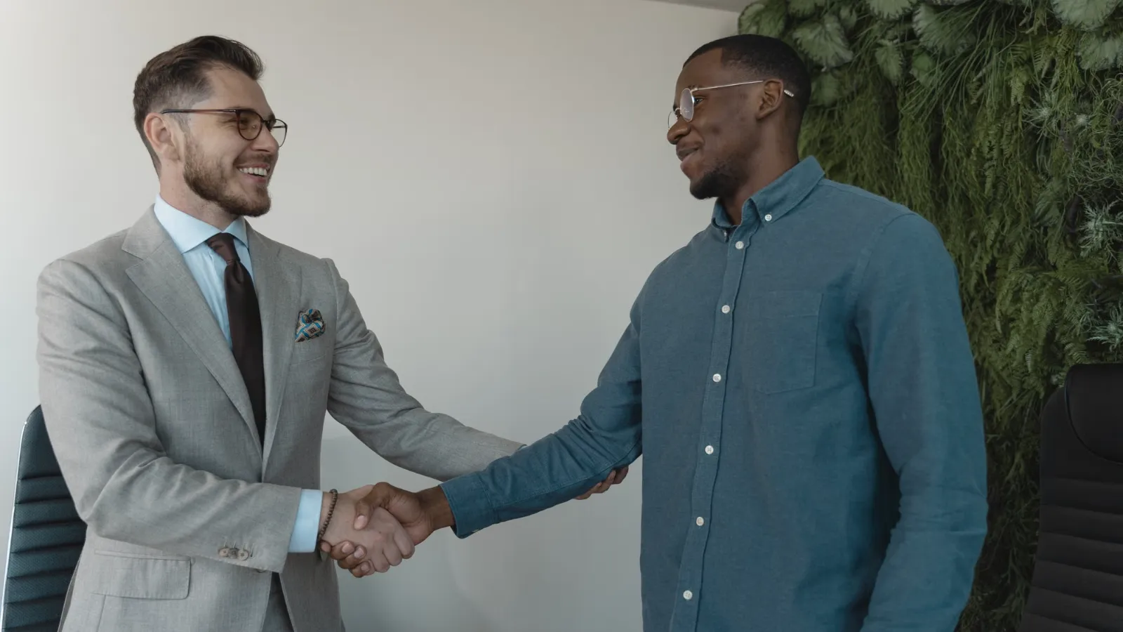 Two businessmen shaking hands and smiling after agreeing a deal